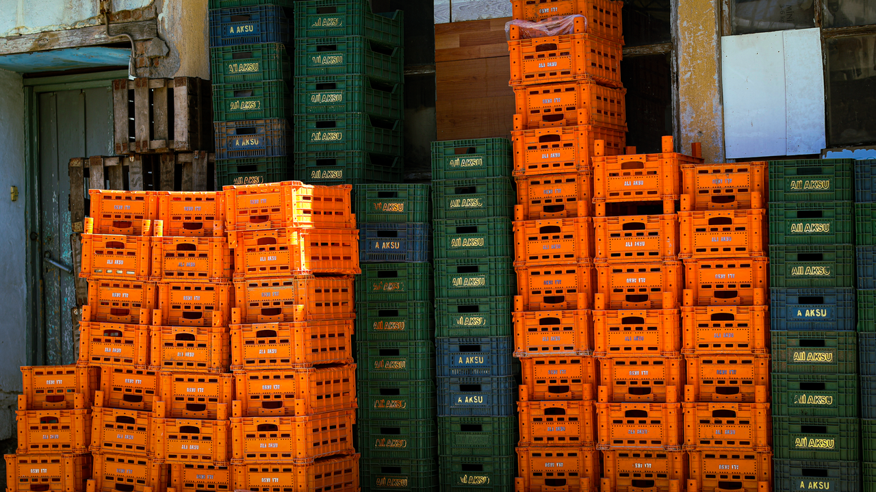 Colorful stacks of orange and green crates outside a warehouse.